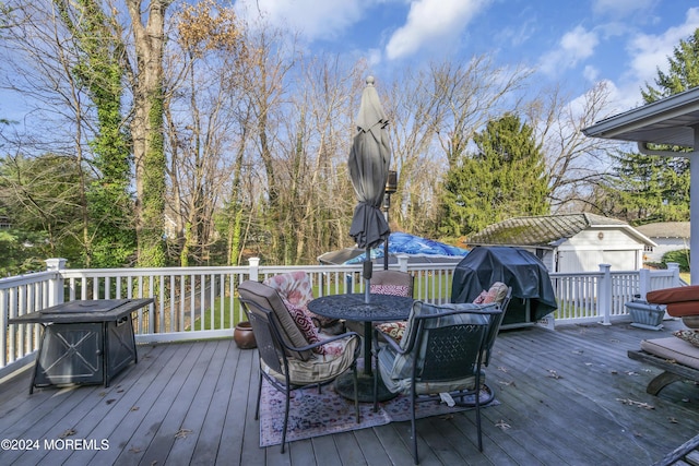 wooden terrace featuring a grill and a storage shed