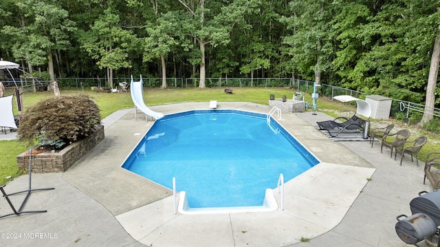 view of pool featuring a yard, a patio, a diving board, and a water slide