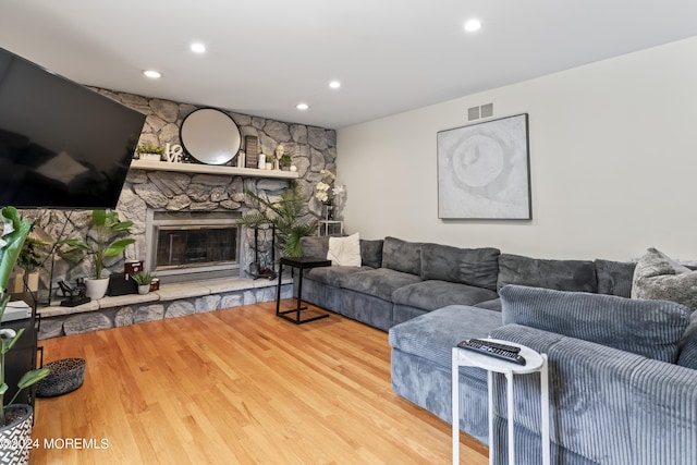 living room featuring hardwood / wood-style flooring and a stone fireplace