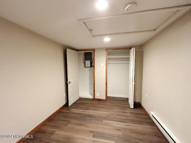 unfurnished bedroom with wood-type flooring, a closet, and a baseboard heating unit