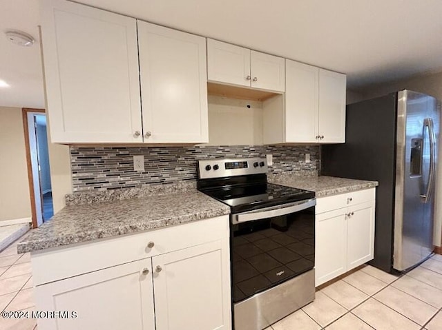 kitchen with white cabinets, light stone countertops, appliances with stainless steel finishes, tasteful backsplash, and light tile patterned flooring