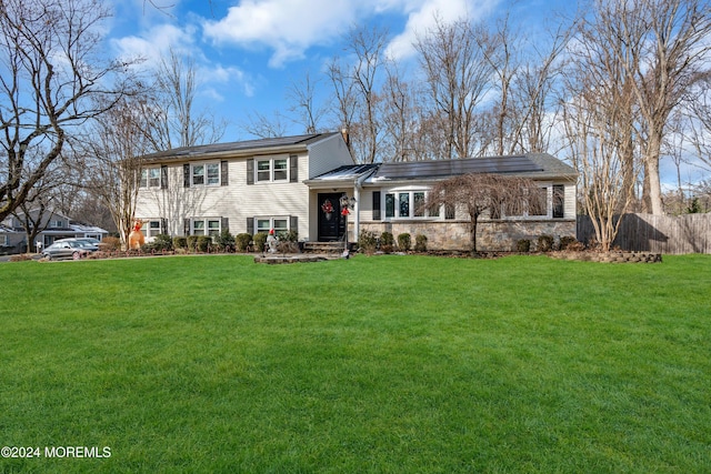 tri-level home with a front yard and solar panels