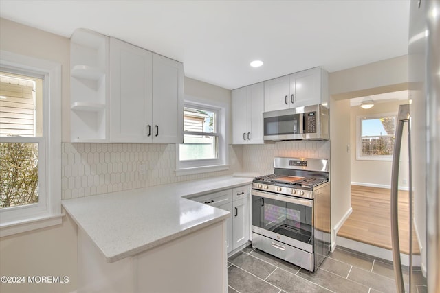 kitchen with light stone countertops, dark wood-type flooring, stainless steel appliances, tasteful backsplash, and white cabinets