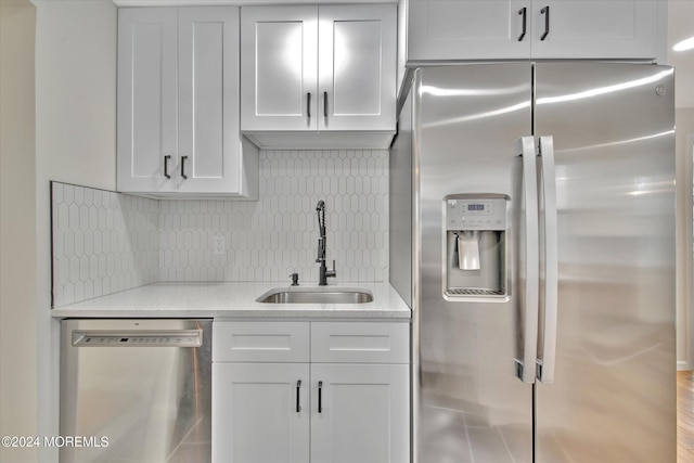 kitchen with wood-type flooring, sink, decorative backsplash, appliances with stainless steel finishes, and white cabinetry