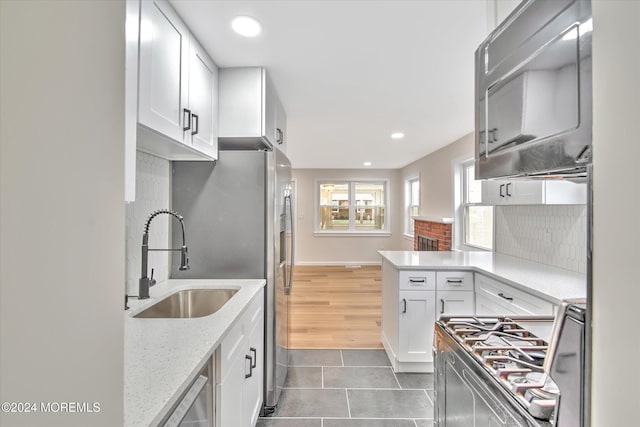 kitchen with tasteful backsplash, white cabinetry, sink, and stainless steel stove