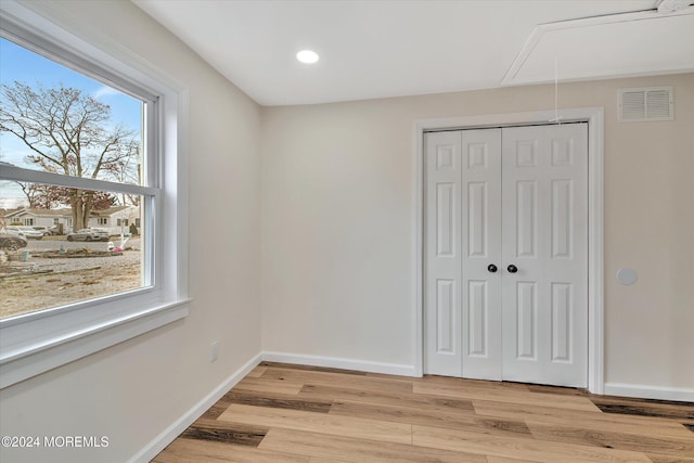 unfurnished bedroom with a closet, light hardwood / wood-style flooring, and multiple windows