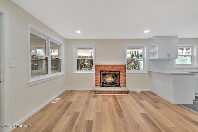 unfurnished living room with a fireplace, plenty of natural light, and light hardwood / wood-style floors