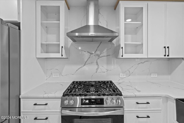 kitchen featuring white cabinets, light stone counters, wall chimney range hood, and stainless steel appliances