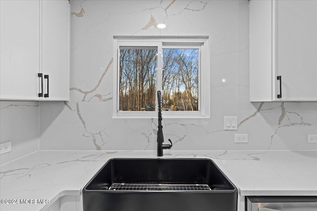 kitchen featuring white cabinetry, tasteful backsplash, light stone counters, and sink