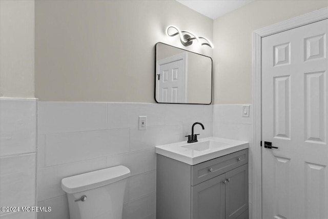 bathroom with vanity, tile walls, and toilet