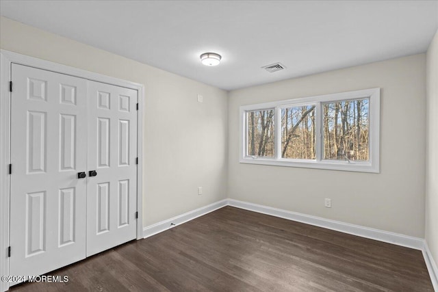 unfurnished bedroom with dark hardwood / wood-style floors and a closet