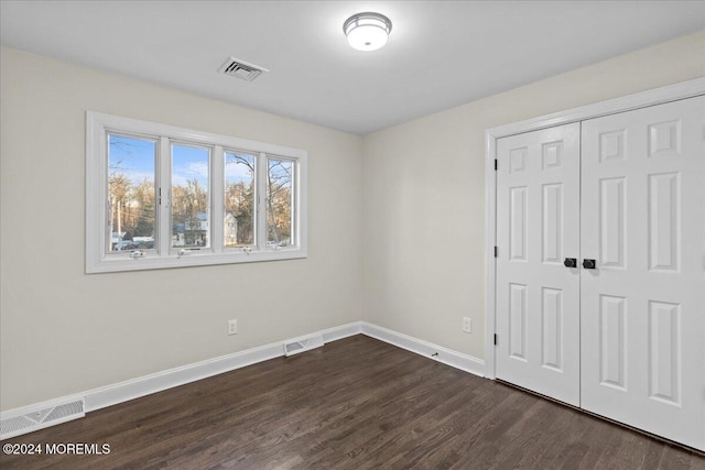 unfurnished bedroom featuring a closet and dark hardwood / wood-style floors