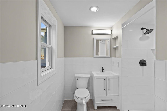 bathroom with walk in shower, tile patterned flooring, toilet, vanity, and tile walls