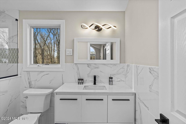 bathroom with vanity, tile walls, and toilet