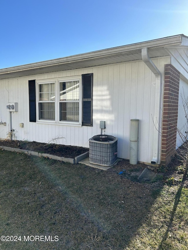 view of side of home with a lawn and cooling unit