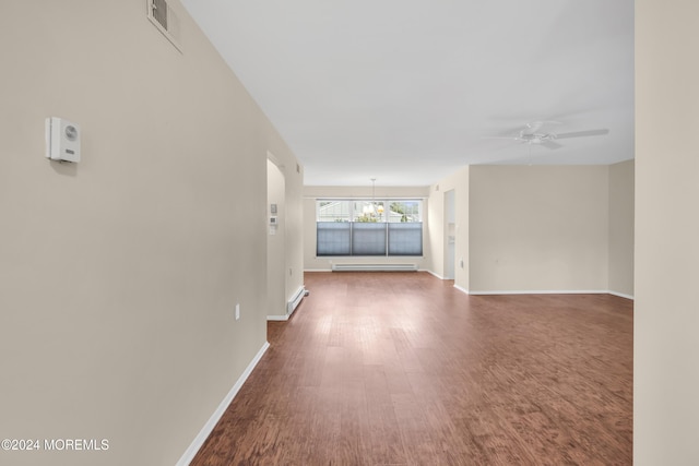 unfurnished living room with hardwood / wood-style floors, ceiling fan with notable chandelier, and a baseboard heating unit