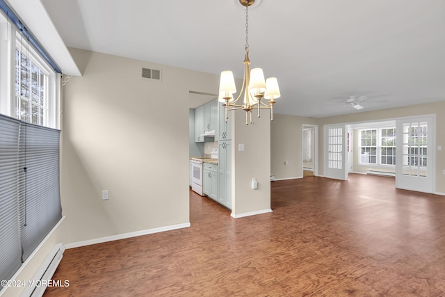 unfurnished dining area featuring ceiling fan with notable chandelier, dark hardwood / wood-style floors, and a baseboard heating unit