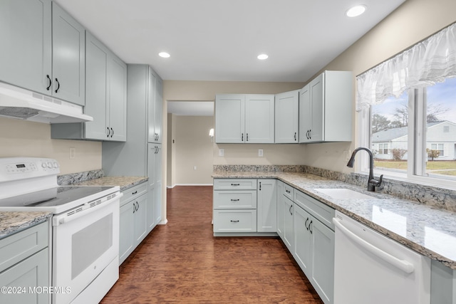 kitchen with light stone counters, white appliances, sink, dark hardwood / wood-style floors, and white cabinetry