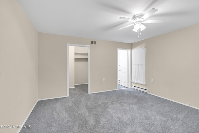 unfurnished bedroom featuring carpet flooring, ceiling fan, a baseboard radiator, a spacious closet, and a closet