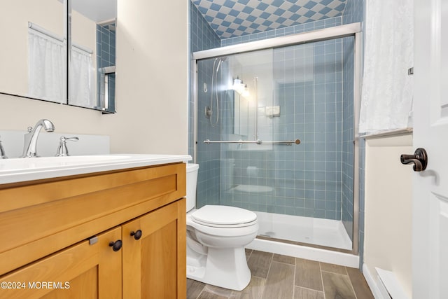 bathroom featuring vanity, toilet, and a shower with shower door