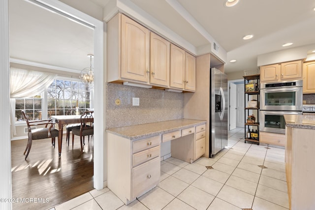 kitchen with light brown cabinets, an inviting chandelier, decorative backsplash, light tile patterned flooring, and stainless steel appliances