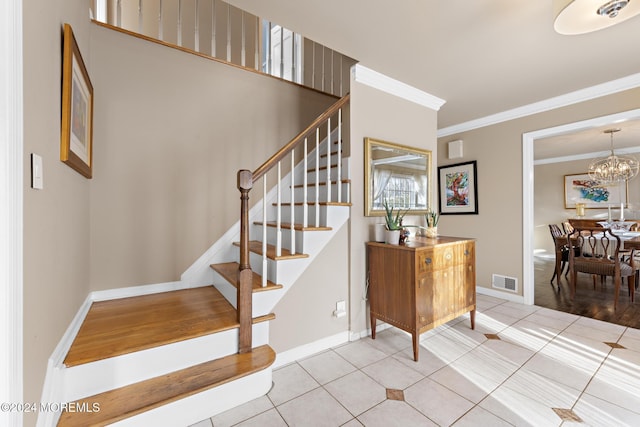 stairs with a chandelier, tile patterned floors, and ornamental molding