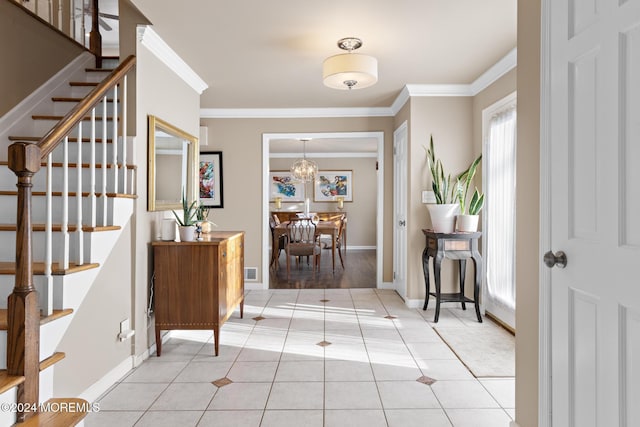 tiled entrance foyer with a chandelier and crown molding