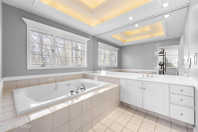 bathroom featuring ornamental molding, vanity, a tray ceiling, a relaxing tiled tub, and tile patterned flooring