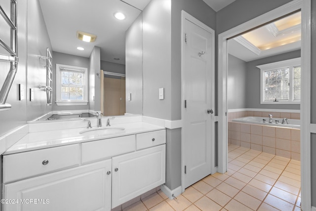 bathroom featuring tile patterned flooring, vanity, a relaxing tiled tub, and a healthy amount of sunlight