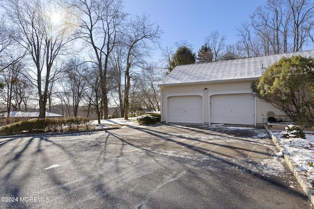 snow covered property featuring a garage and an outdoor structure