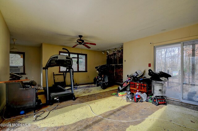 exercise area with cooling unit, a wealth of natural light, and ceiling fan