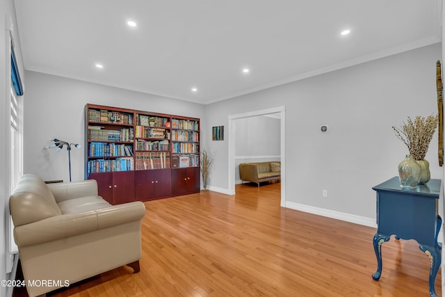 living area with wood-type flooring and ornamental molding