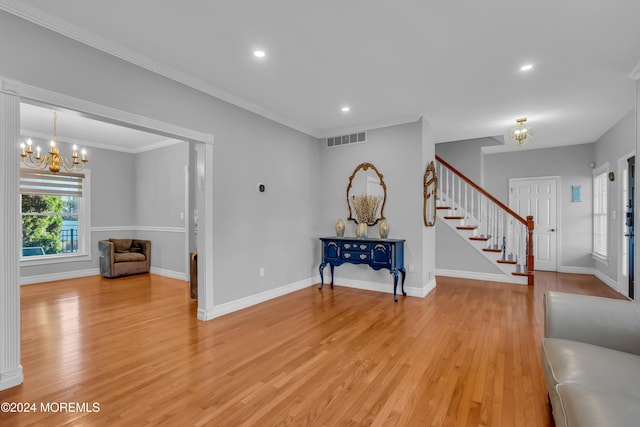 entrance foyer featuring a chandelier, light wood-type flooring, and crown molding