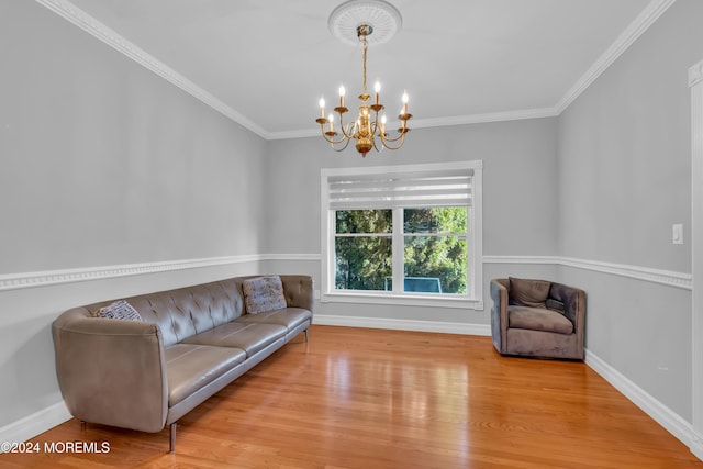 living area with crown molding, light hardwood / wood-style flooring, and an inviting chandelier