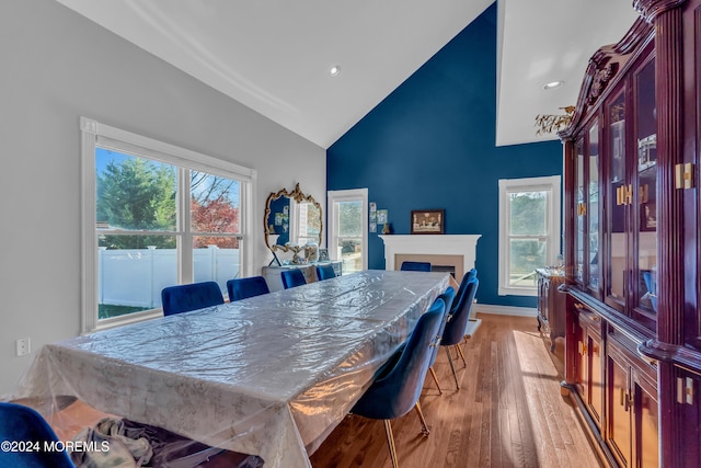 dining space with high vaulted ceiling and light hardwood / wood-style floors