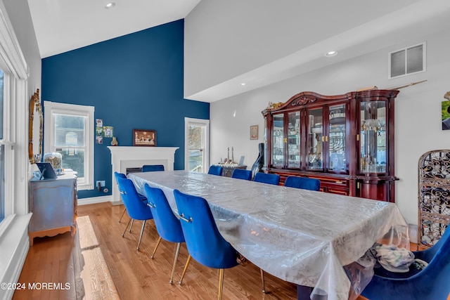 dining space featuring light wood-type flooring, high vaulted ceiling, and a healthy amount of sunlight