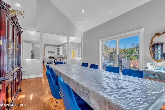 dining area with high vaulted ceiling and light hardwood / wood-style flooring