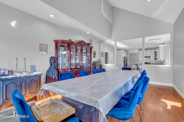 dining room featuring light wood-type flooring and high vaulted ceiling