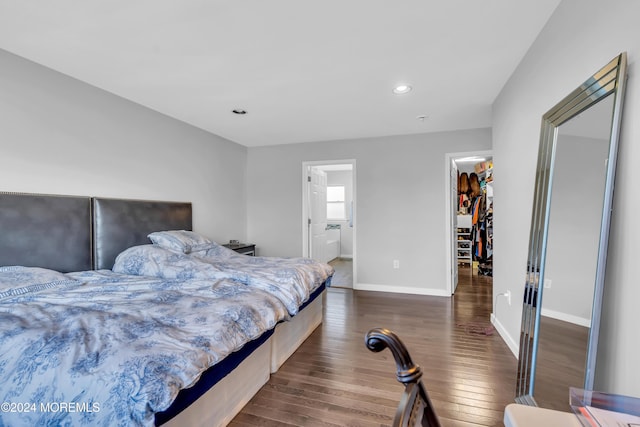 bedroom featuring ensuite bathroom, a spacious closet, a closet, and dark wood-type flooring