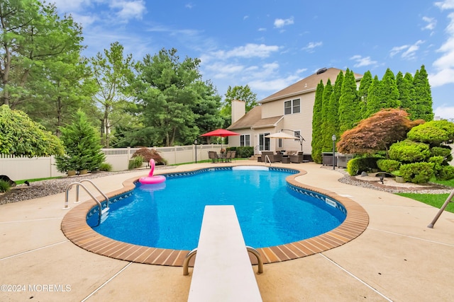 view of pool with a diving board and a patio area