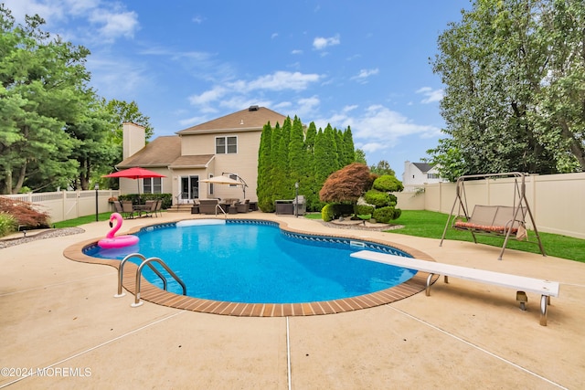 view of swimming pool with a diving board and a patio area