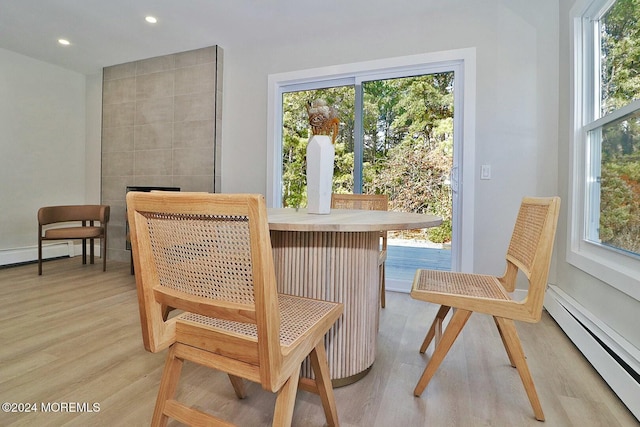 living area featuring a healthy amount of sunlight, light wood-type flooring, and a baseboard heating unit