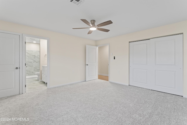 unfurnished bedroom with ceiling fan, ensuite bathroom, light carpet, and a closet