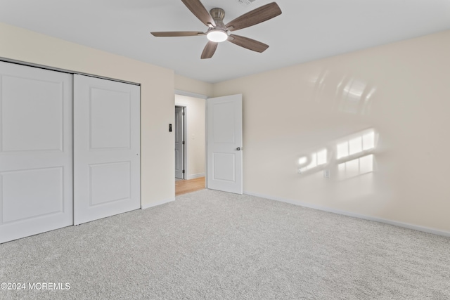 unfurnished bedroom featuring ceiling fan, light carpet, and a closet