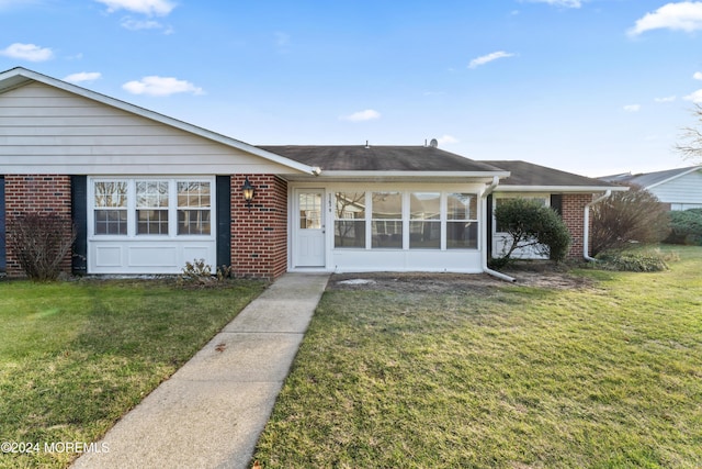 ranch-style house with a sunroom and a front lawn