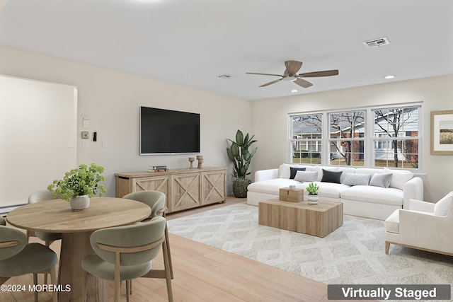 living room with baseboard heating, ceiling fan, and light hardwood / wood-style flooring