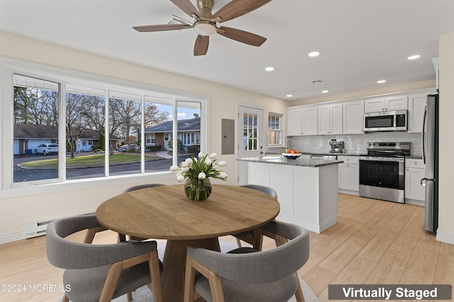 kitchen with dark stone counters, light hardwood / wood-style flooring, appliances with stainless steel finishes, a kitchen island, and white cabinetry