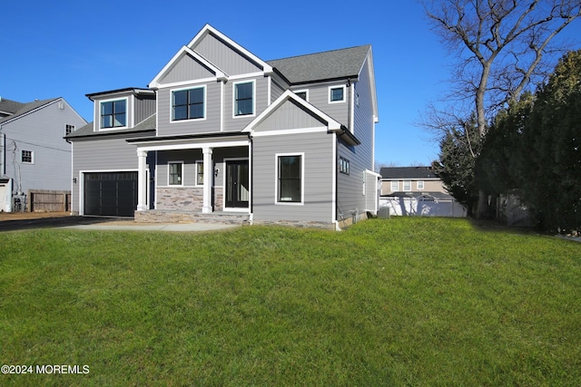 view of front facade with covered porch, a front yard, and a garage