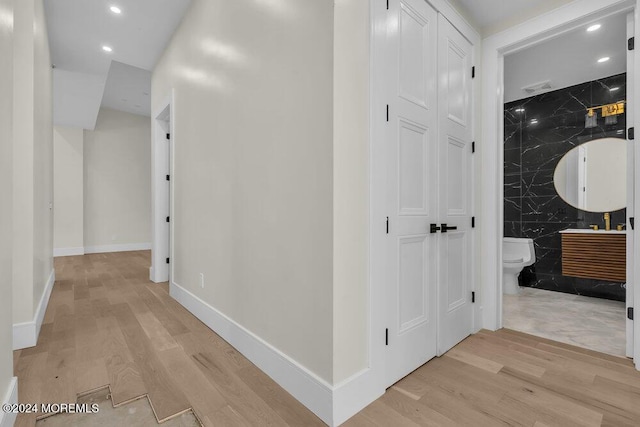 hall with light hardwood / wood-style floors and tile walls