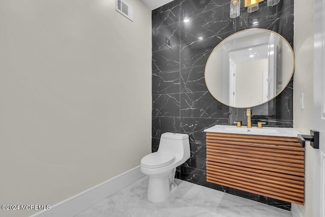 bathroom with vanity, toilet, and tile walls